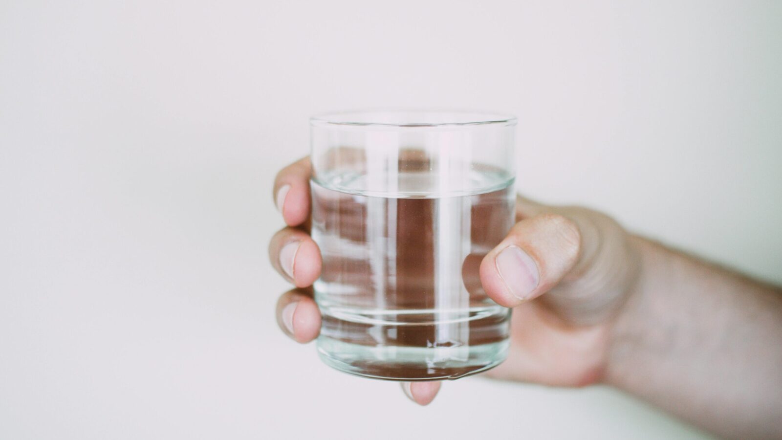 Ein Glas mit klarer Flüssigkeit in einer rechten Hand
