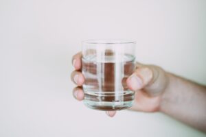 Ein Glas mit klarer Flüssigkeit in einer rechten Hand