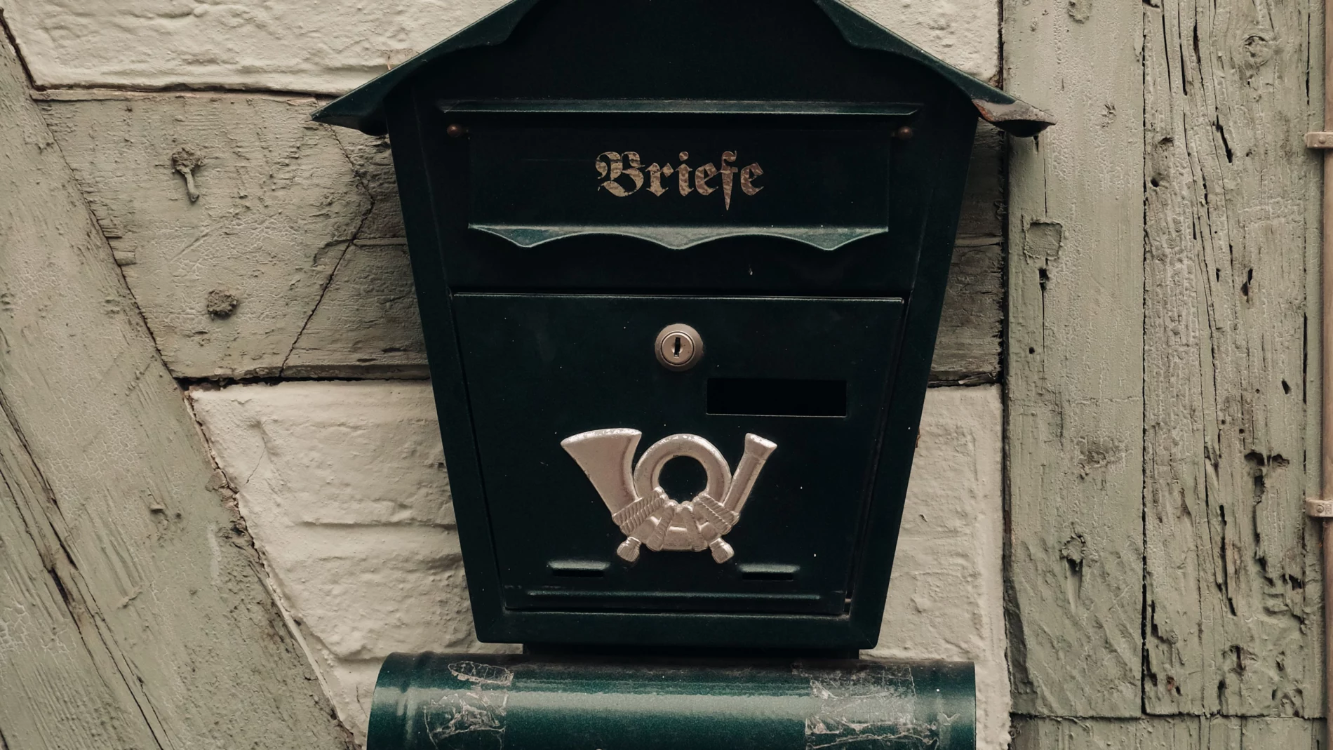 Briefkasten an einer Wand mit Vorladung von der Polizei